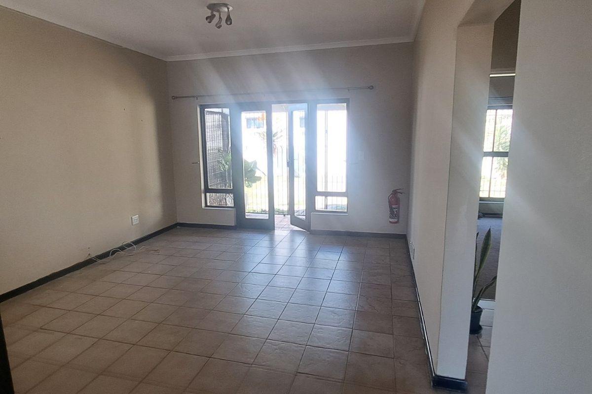 An empty, tiled living room featuring a sliding glass door that provides natural light and access to the exterior.
