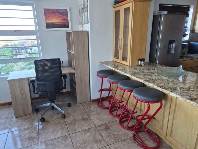 Kitchen area featuring granite countertops, built-in cabinetry, and tiled flooring, with an integrated breakfast bar and adjacent workspace.