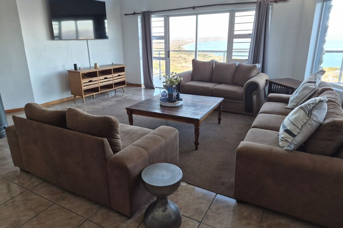 Spacious living room featuring tiled flooring, high ceilings, and large sliding glass doors that offer expansive coastal views.