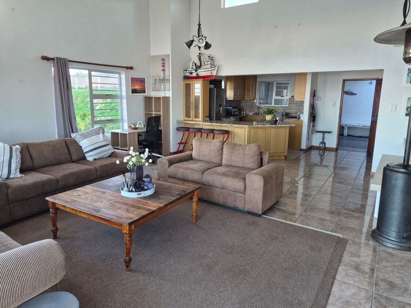 Spacious open-plan living area featuring tiled floors, high ceilings, a cozy fireplace, and a functional kitchen with granite countertops and breakfast bar.