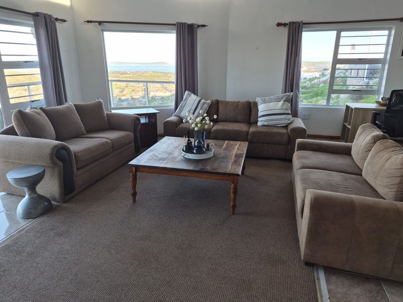Spacious living room featuring large windows with scenic views, neutral wall finishes, and tiled flooring, offering a bright and comfortable atmosphere.