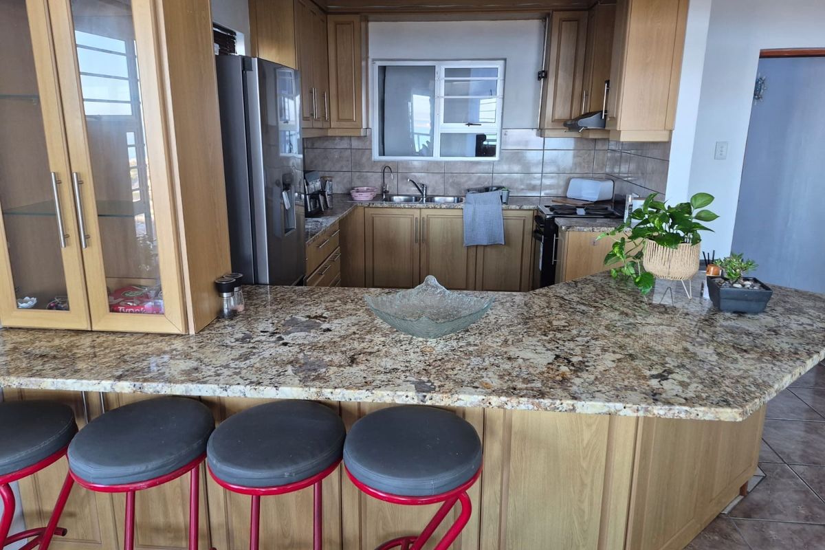 A functional kitchen featuring wooden cabinetry, granite countertops, a tiled backsplash, and integrated appliances, offering a classic layout with a breakfast bar.