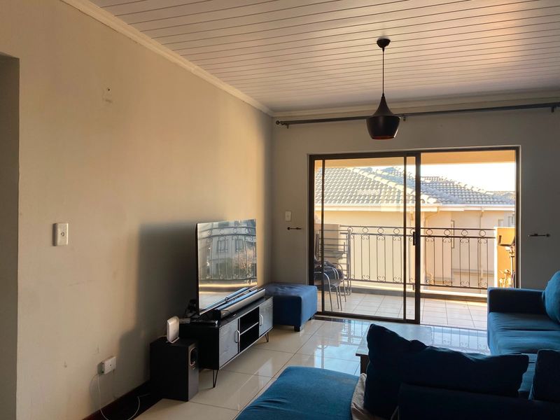 A living room featuring tiled floors, a tongue and groove ceiling, and a sliding glass door providing access to a balcony.