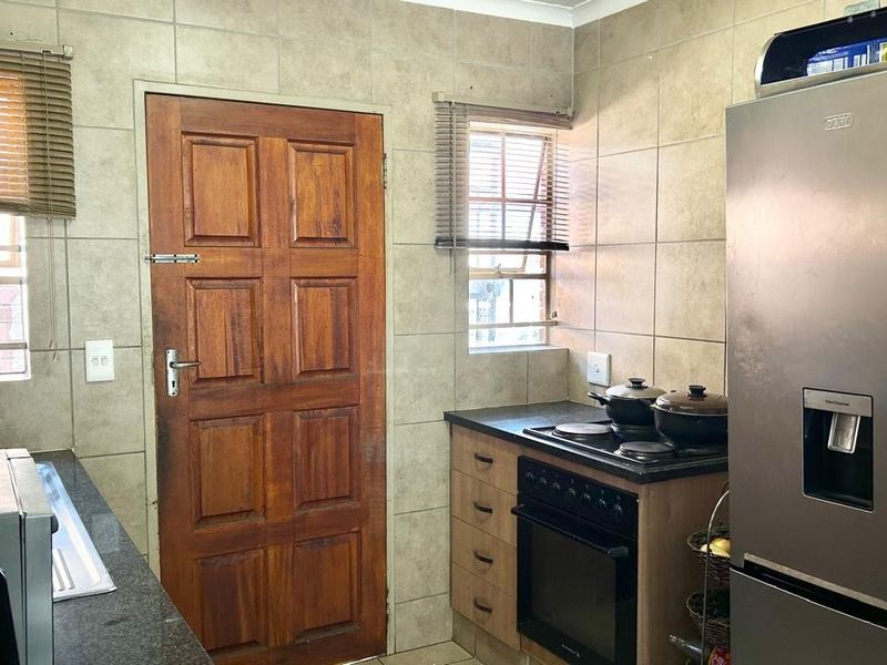 A functional kitchen featuring tiled walls, granite countertops, built-in cabinetry, and a built-in oven with an electric hob.