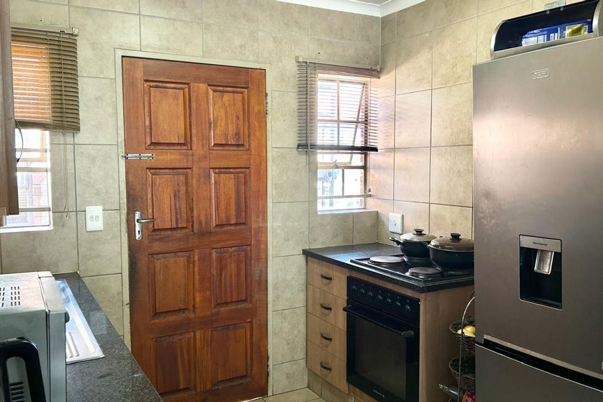 A functional kitchen featuring tiled walls, granite countertops, built-in cabinetry, and a built-in oven with an electric hob.