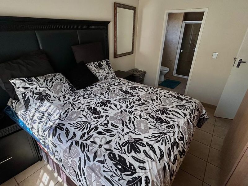 A bedroom featuring tiled flooring, a built-in wardrobe, and an adjoining en-suite bathroom.