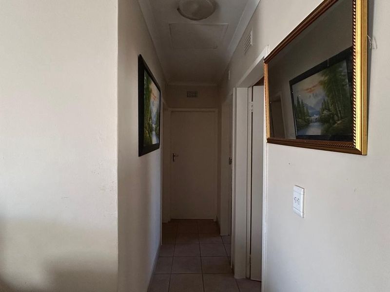 A functional residential hallway featuring tiled flooring and access to multiple internal rooms.