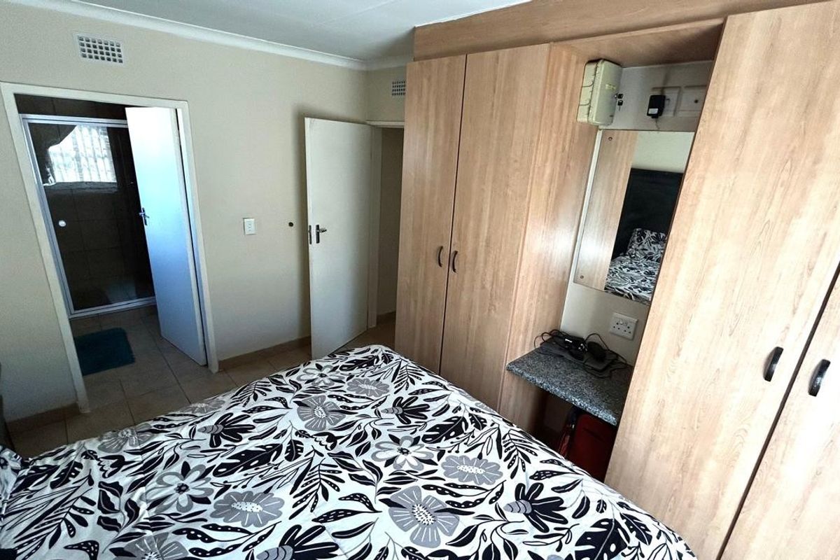 Bedroom featuring light wood built-in cupboards with an integrated vanity area and direct access to an en-suite bathroom.