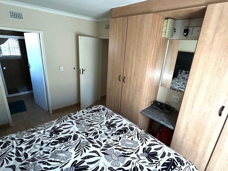 Bedroom featuring light wood built-in cupboards with an integrated vanity area and direct access to an en-suite bathroom.