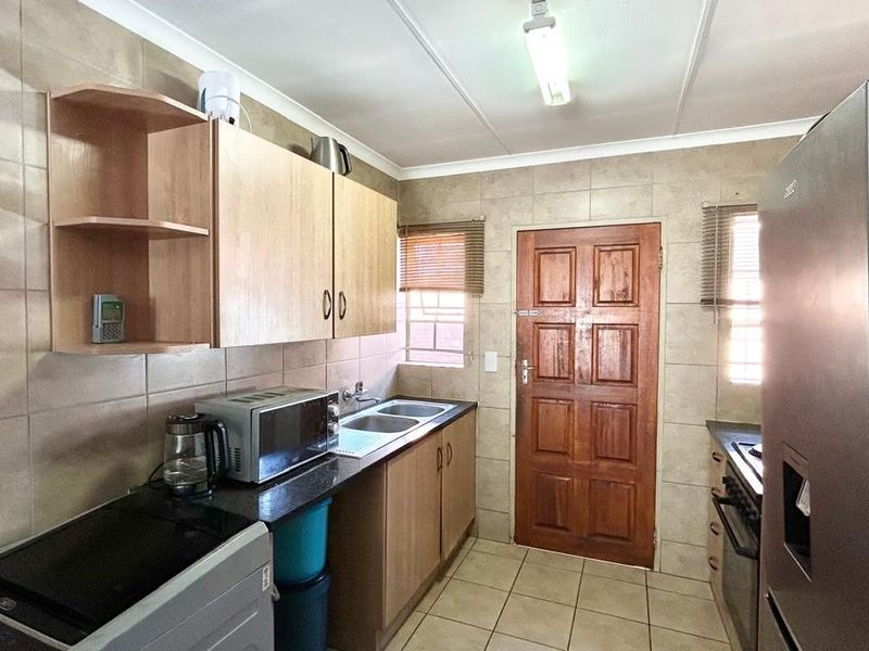 A functional kitchen featuring tiled walls and flooring, built-in cabinetry, a double sink, and integrated cooking appliances.