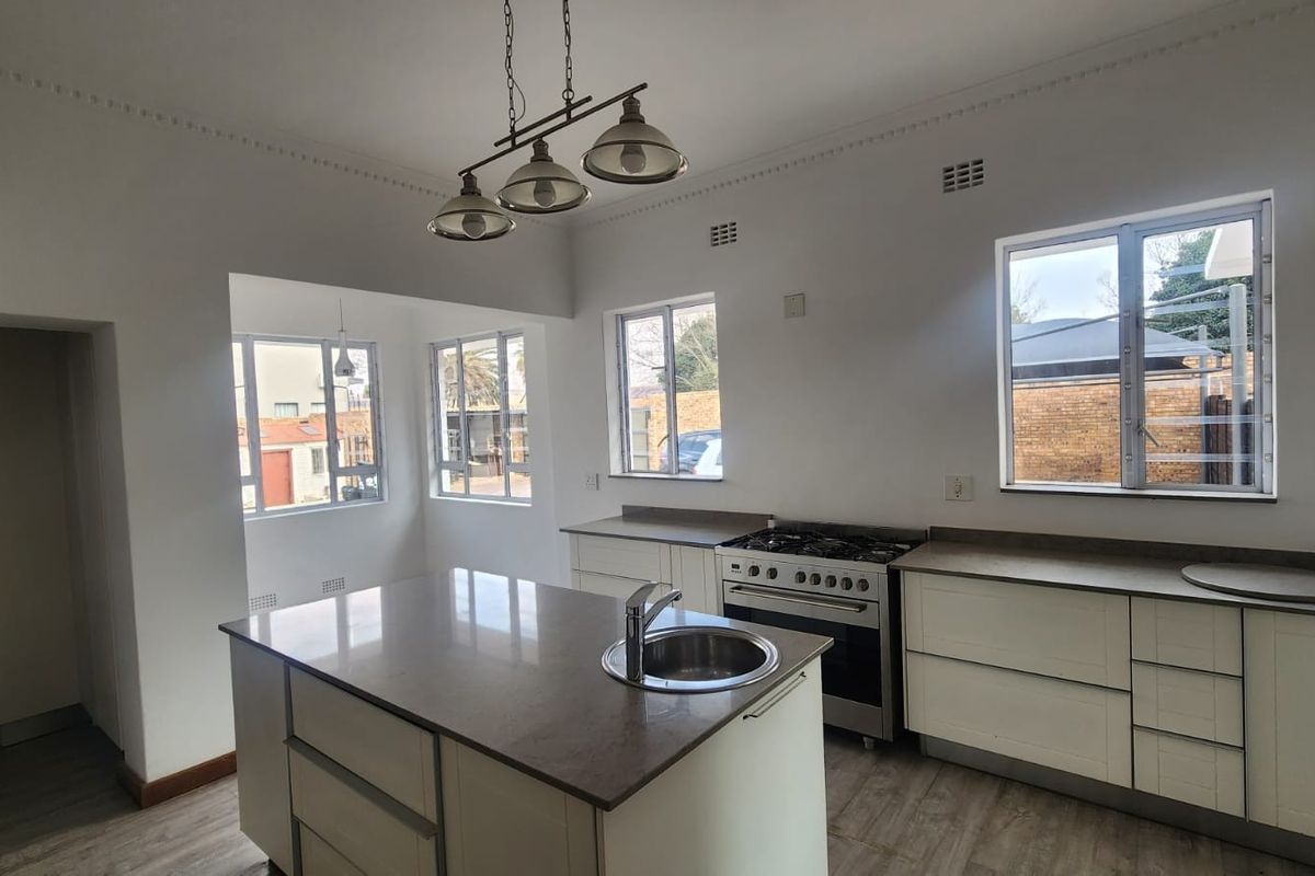 Modern kitchen featuring a central island with an integrated sink, stone countertops, gas stove, and ample built-in cabinetry in a bright, open space.