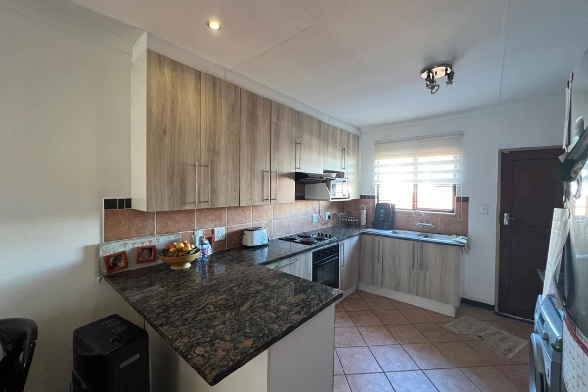 Functional kitchen featuring laminate cabinetry, granite countertops, built-in oven, hob, extractor fan, and tiled flooring.