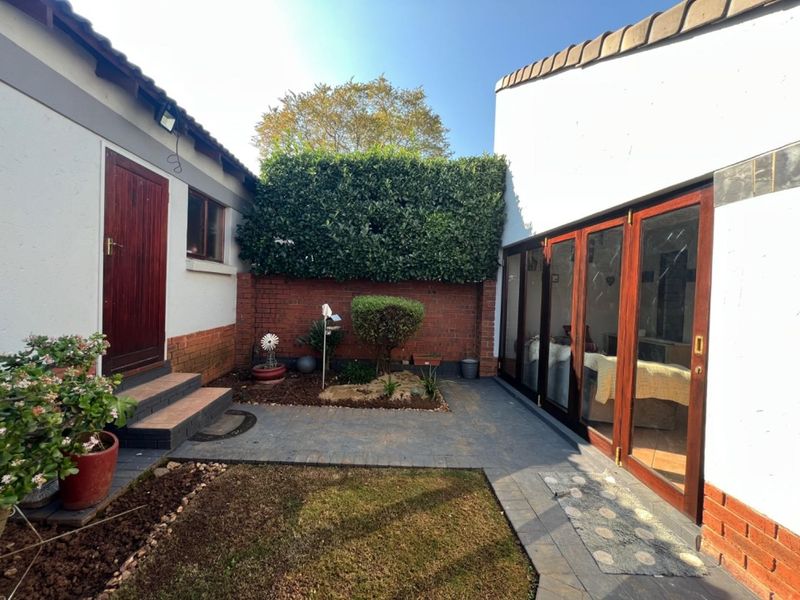 A private rear courtyard featuring paved flooring, a brick boundary wall, and timber-framed folding doors providing seamless access to the interior living space.