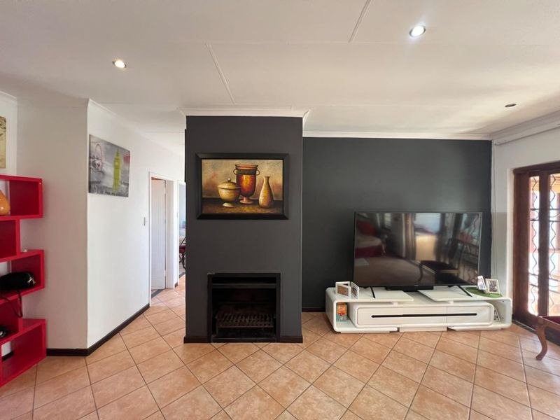 Living room featuring a dark accent wall with a built-in fireplace, tiled flooring, and access to an outdoor area through a sliding glass door.