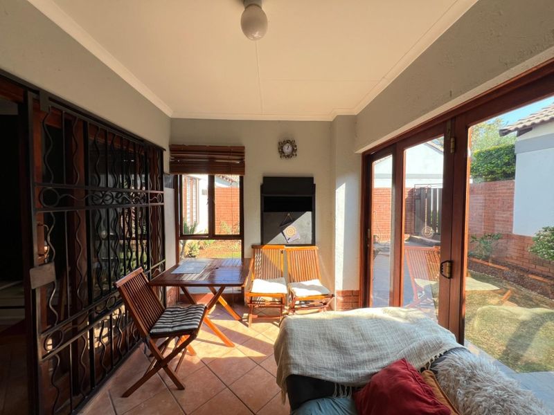 Enclosed patio area featuring tiled flooring, a built-in braai, and large sliding glass doors providing direct access to the rear garden.