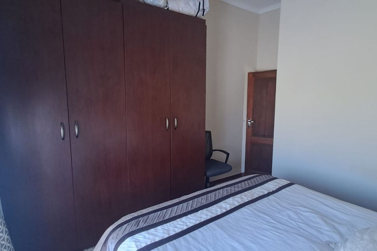 A bedroom featuring a large dark wood built-in wardrobe and a solid timber door.