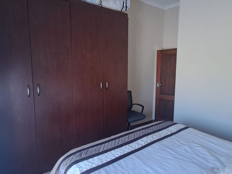 A bedroom featuring a large dark wood built-in wardrobe and a solid timber door.