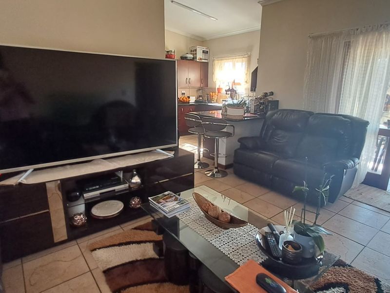 Open-plan living area featuring tiled flooring, a kitchen with breakfast bar, and direct access to an outdoor patio through sliding glass doors.