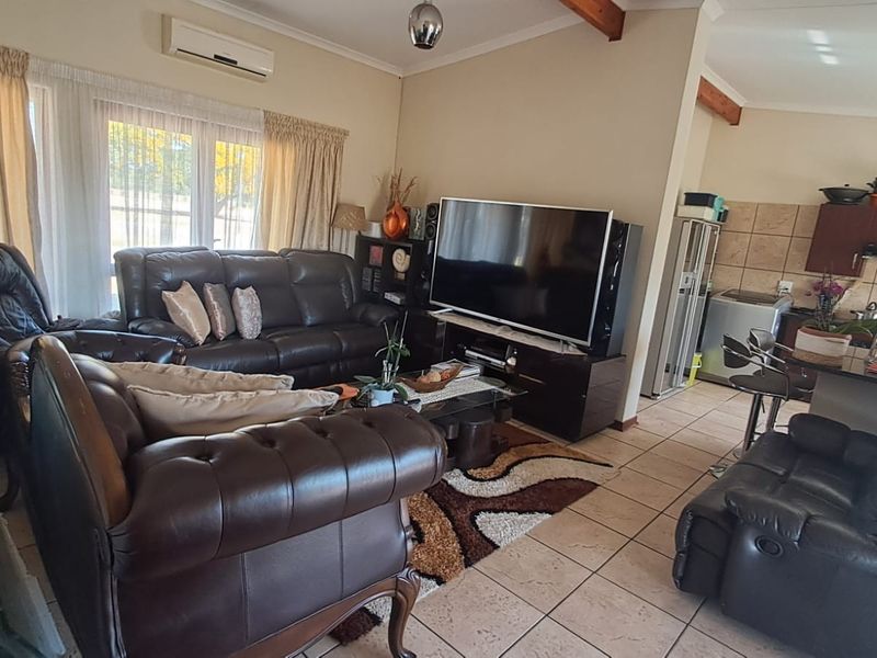 Open-plan living and kitchen area featuring tiled floors, exposed timber ceiling beams, and a split-system air conditioner, offering a functional layout.