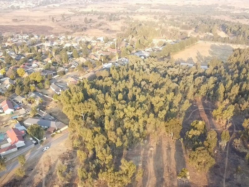 Aerial view of a vacant residential land parcel featuring mature trees and proximity to established suburban housing.