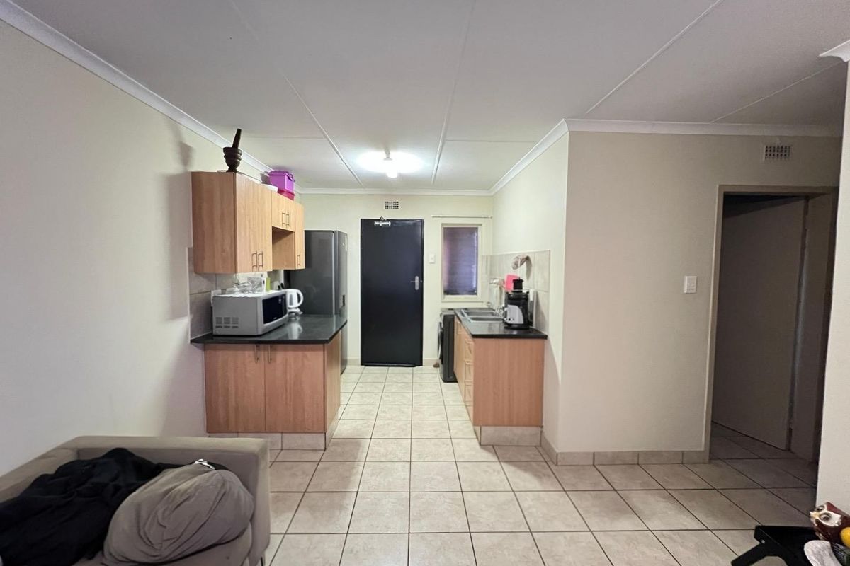 Open plan kitchen area featuring laminate cabinetry, tiled flooring, and a double basin sink, providing a functional layout for the apartment.