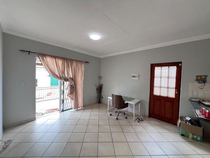 Open plan living area featuring tiled flooring, a timber entrance door, and a sliding door providing access to an outdoor patio area.