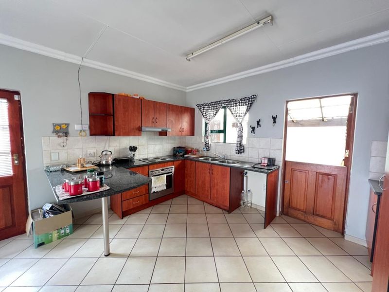 A functional kitchen featuring wooden cabinetry, granite countertops, built-in oven, and tiled flooring with direct access to the exterior.