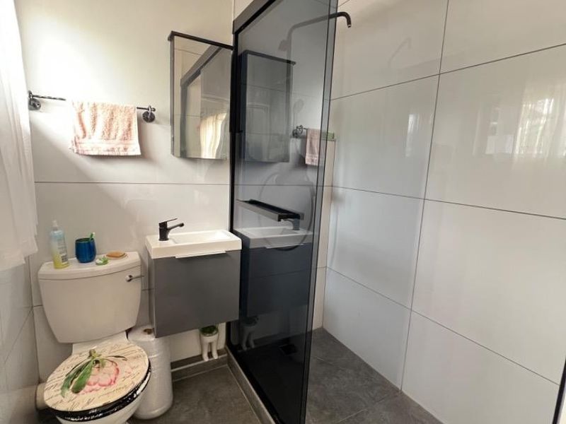 Modern bathroom featuring a walk-in shower with a black-framed glass screen, wall-mounted vanity, and neutral tiled finishes throughout.