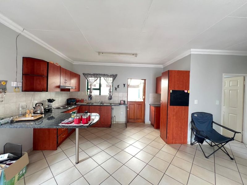 A functional kitchen featuring granite countertops, ample wooden cabinetry, tiled flooring, and direct access to an exterior door.