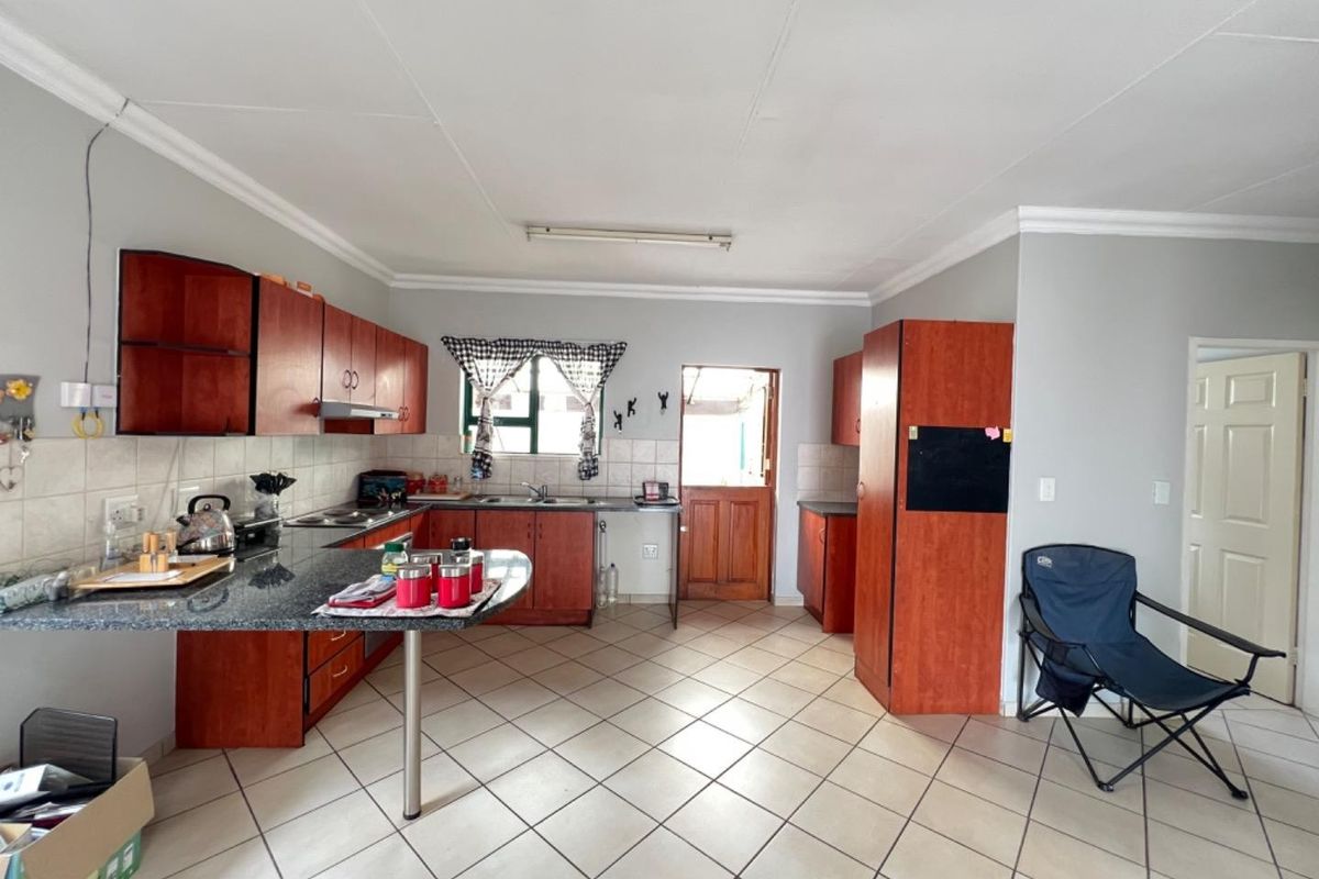 A functional kitchen featuring granite countertops, ample wooden cabinetry, tiled flooring, and direct access to an exterior door.