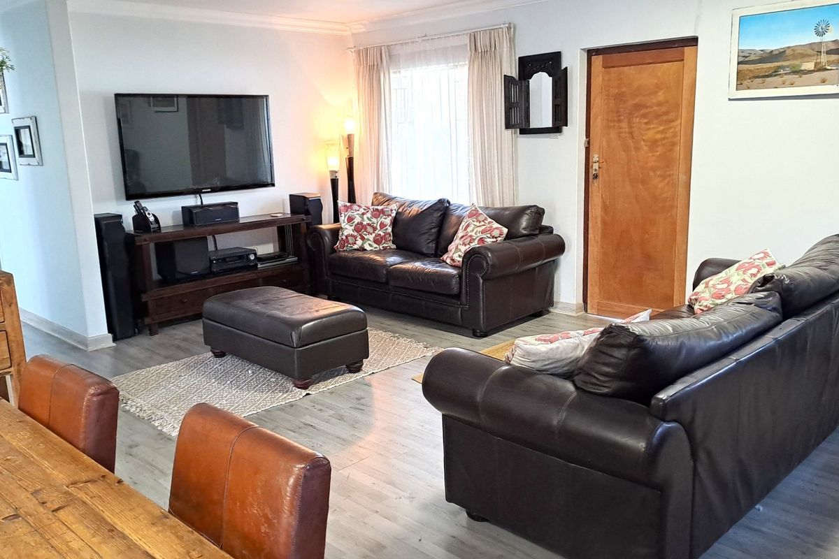 A comfortable living room featuring light-toned laminate flooring, neutral walls, and a classic timber door, providing a functional and inviting space.