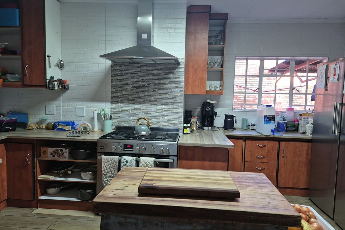 A functional kitchen featuring wooden cabinetry, a gas stove with a stainless steel extractor fan, and a tiled backsplash.