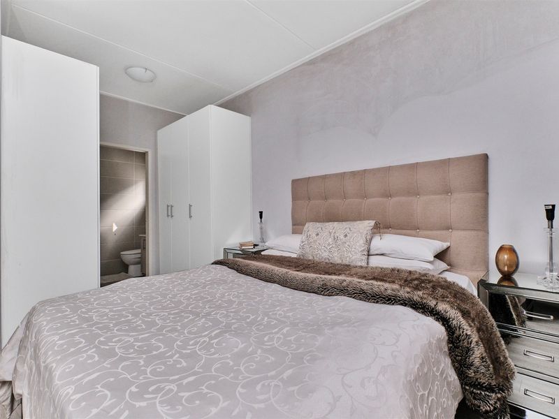 A well-maintained bedroom featuring built-in wardrobes and an en-suite bathroom access, offering a clean and functional living space.