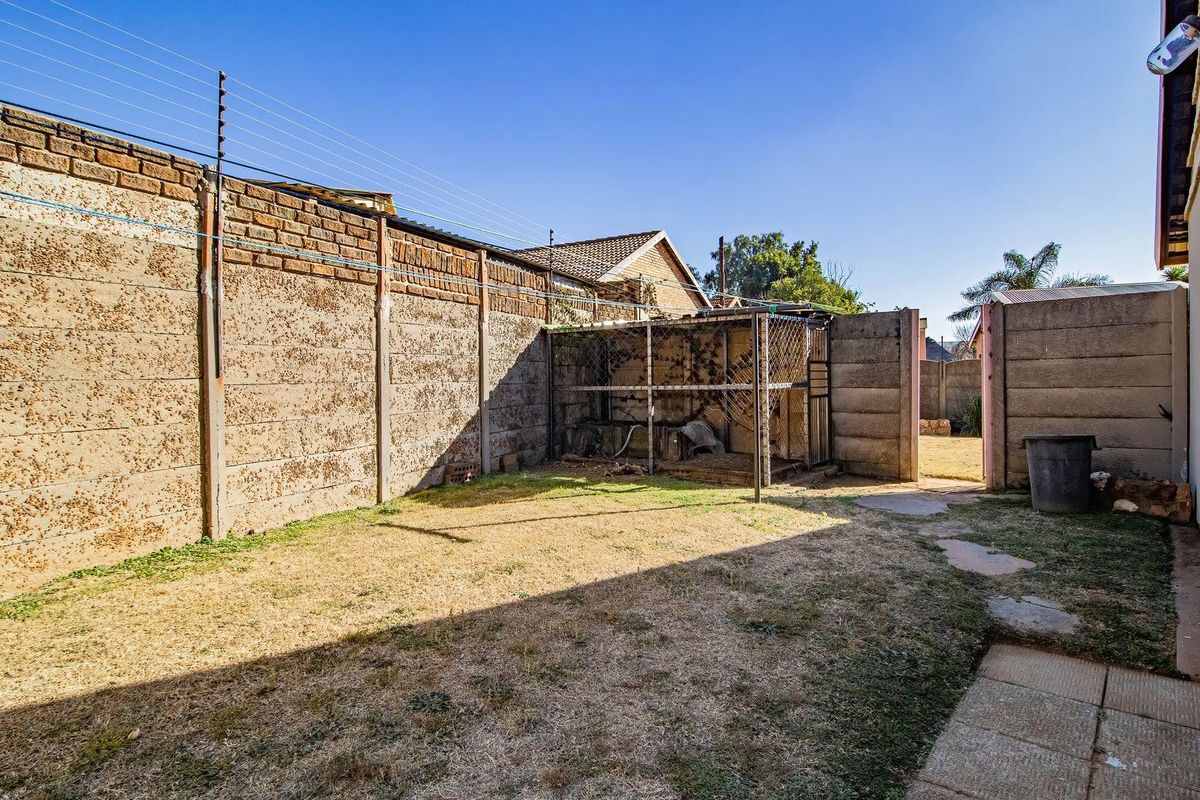 A rear exterior view of the property featuring a precast concrete boundary wall with electric fencing and a small metal enclosure.