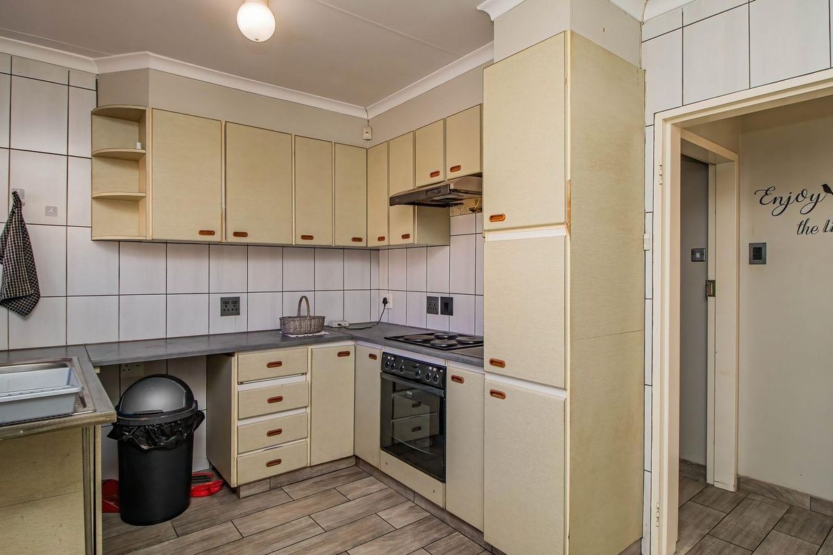 A functional kitchen featuring built-in cabinetry, an electric oven and hob, extractor fan, and tiled backsplash with a neutral aesthetic.