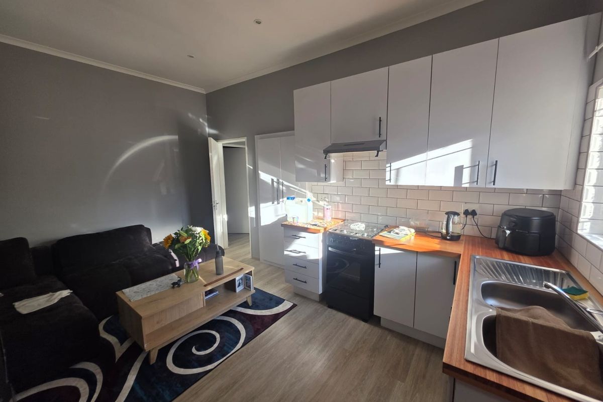 Open-plan living area featuring a modern kitchen with white cabinetry, wooden countertops, subway tile backsplash, and integrated stainless steel sink.