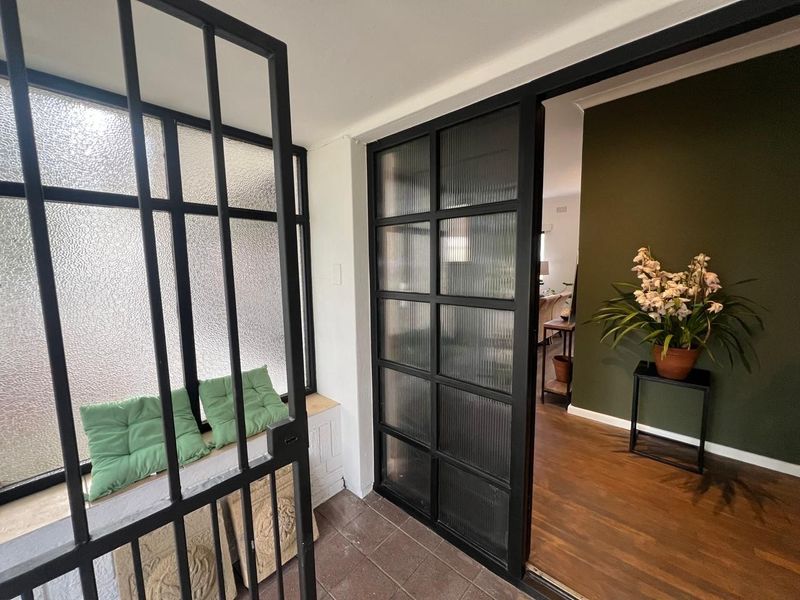 A modern entrance area featuring a stylish black steel-framed glass door with fluted glass panels and durable tiled flooring.
