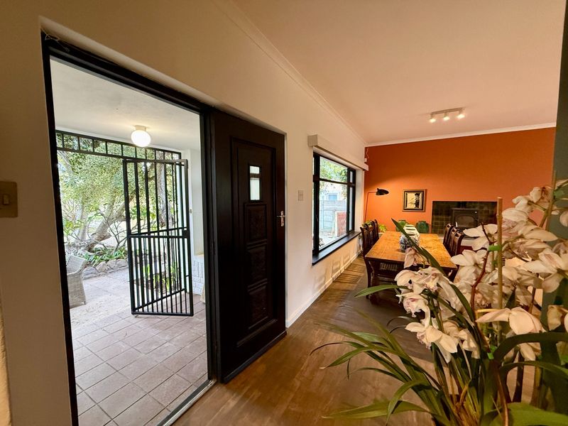 Open plan living and dining area featuring a fireplace, large windows, and direct access to a tiled patio through a secure entrance.