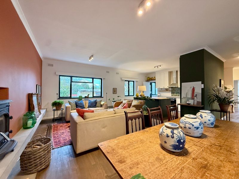 Spacious open-plan living and kitchen area featuring timber flooring, a wood-burning stove, and a modern kitchen with built-in cabinetry and a tiled backsplash.