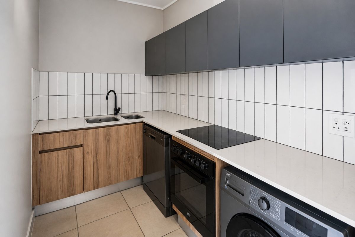 Modern kitchen featuring sleek dark grey upper cabinetry, wood-grain lower cabinets, stone countertops, subway tile backsplash, and integrated appliances.