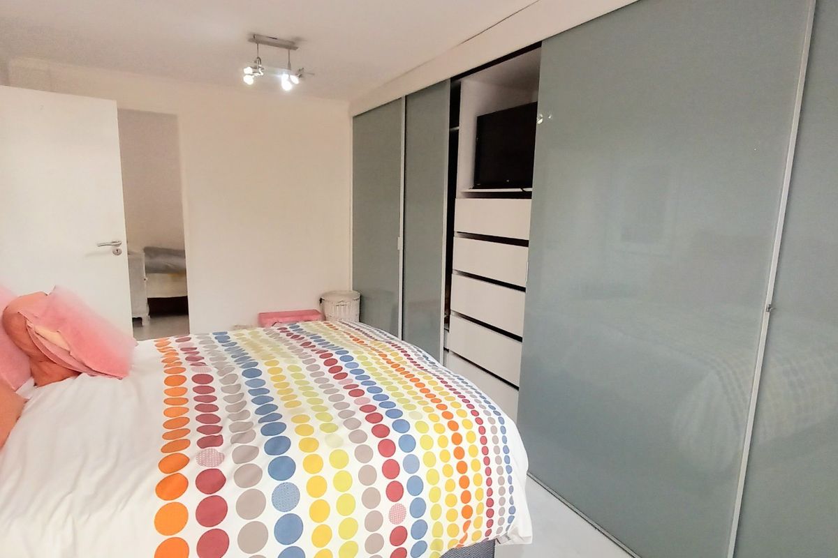 A well-maintained bedroom featuring a large, modern built-in sliding door wardrobe with integrated shelving and storage.