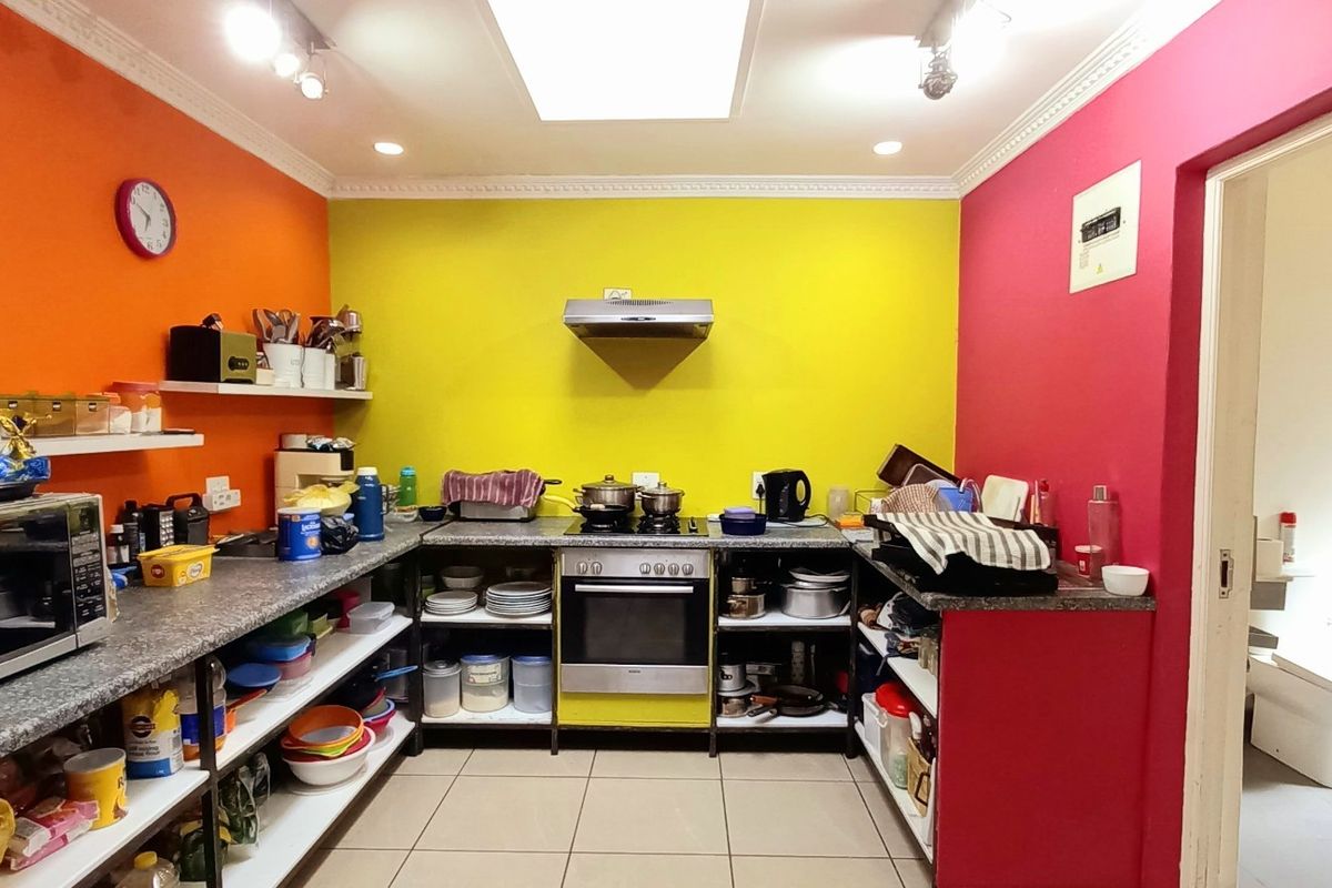 A functional kitchen featuring stone countertops, built-in oven, extractor fan, and tiled flooring, currently finished with vibrant wall colors.