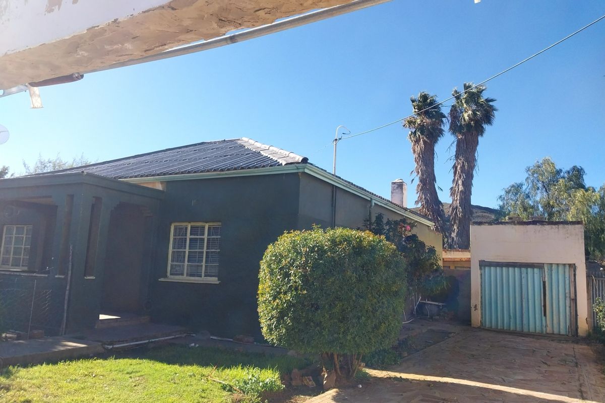 Front view of a detached house featuring a paved driveway, a separate garage, and a small front garden area.