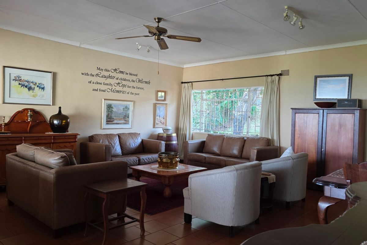 A spacious living room featuring tiled flooring, a ceiling fan, and large windows that provide natural light, creating a comfortable and inviting atmosphere.