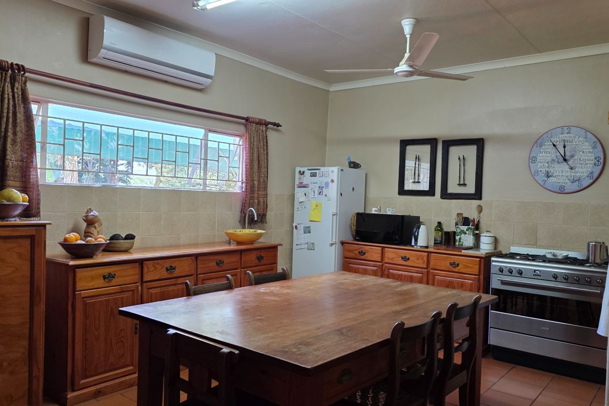 A functional kitchen featuring wooden cabinetry, tiled backsplash, and a freestanding oven, providing a practical workspace with integrated climate control.