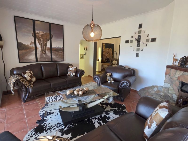 Spacious living room featuring a stone fireplace, terracotta floor tiles, and an open archway leading to adjacent living areas.