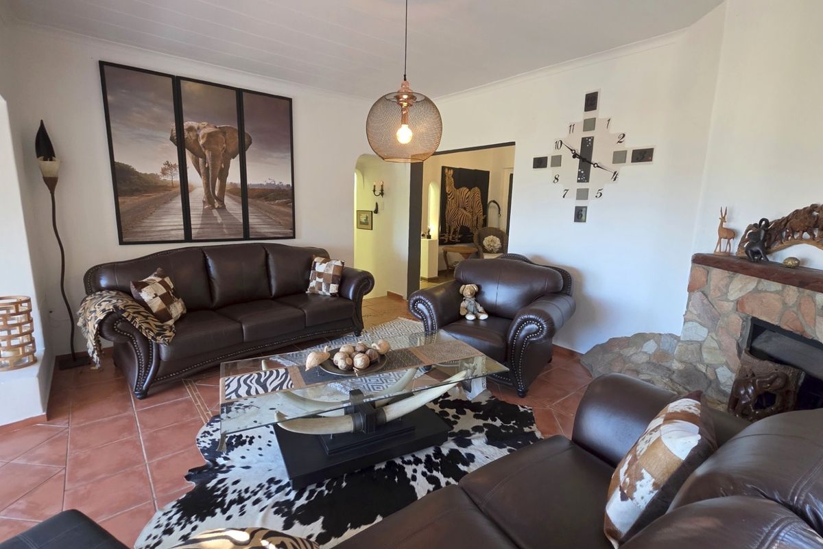 Spacious living room featuring a stone fireplace, terracotta floor tiles, and an open archway leading to adjacent living areas.