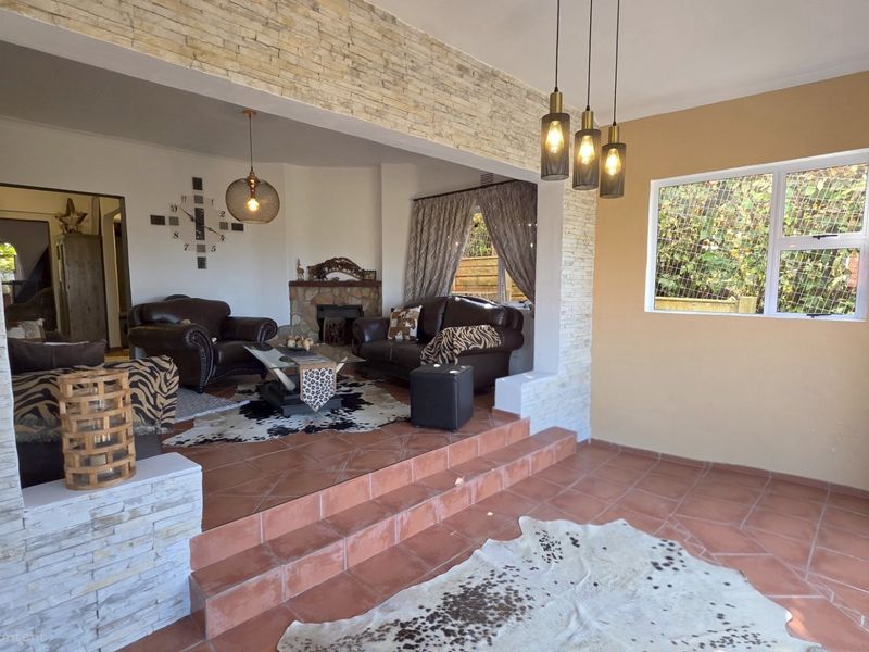An open-plan living area featuring terracotta tiled flooring, stone-clad feature walls, a fireplace, and stepped transitions between living spaces.