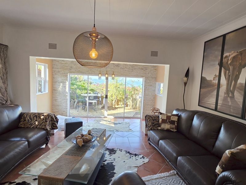Spacious living room featuring tiled flooring, a stone feature wall, and large sliding glass doors that provide natural light and access to the outdoor area.