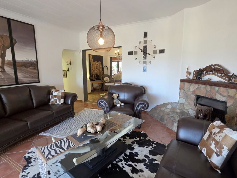 A cozy living room featuring a rustic stone fireplace, tiled flooring, and warm pendant lighting, creating a welcoming atmosphere.